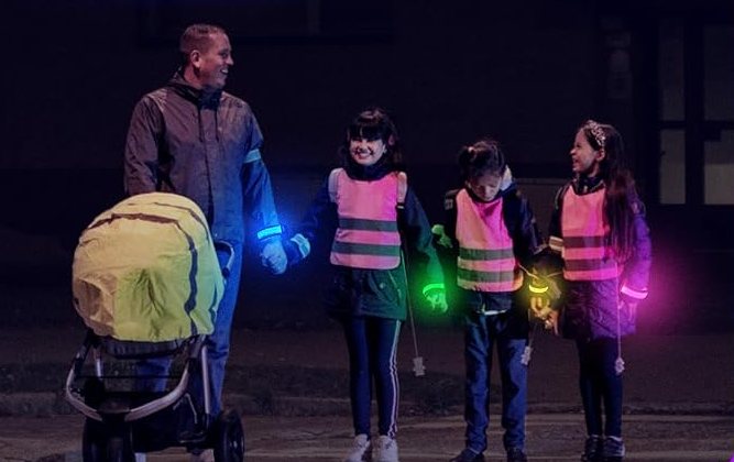 A family wearing FANL glow bracelets on a dark pavement